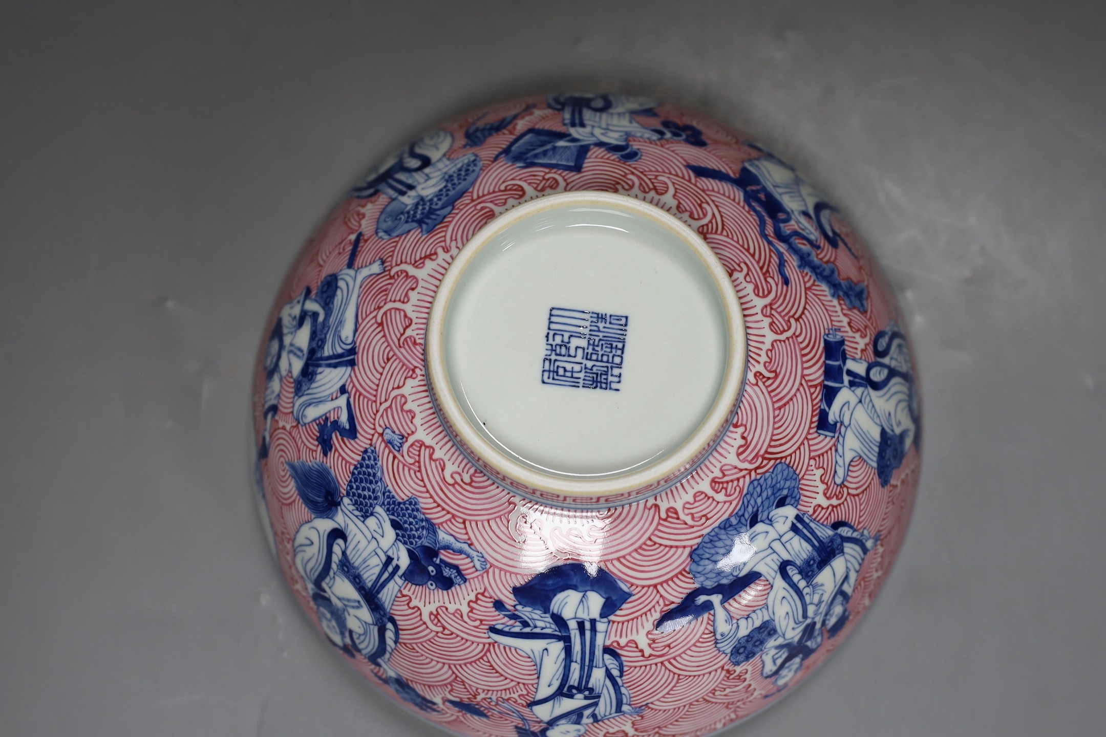 A Chinese underglaze blue and puce enamelled 'eight immortals' bowl, 22cm diameter